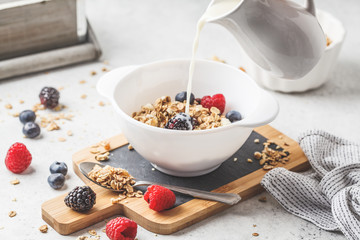 Breakfast food background. Granola with milk and berries on white table.