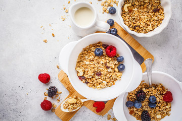Breakfast food background. Granola with milk and berries on white table.