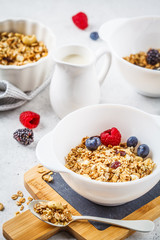 Breakfast food background. Granola with milk and berries on white table.