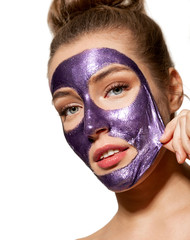Portrait of attractive young model taking care of skin. Skincare and wellness concept. Beautiful woman removing purifying clay mask from face on white background