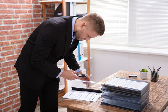 Businessman Taking Photograph In Office