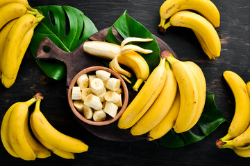 Bananas on a black wooden surface. Tropical Fruits. Top view. Free copy space. - Powered by Adobe