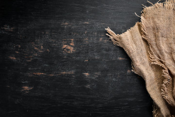 Old linen fabric on a black wooden background.