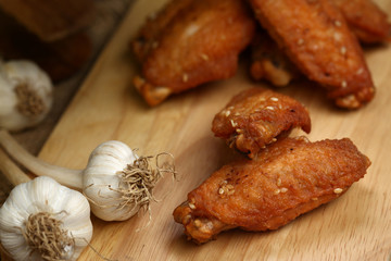 Beautiful plate fried chicken wings on wooden tray with garlic and pepper, selective focus and free copy space. Clean food good taste concept.