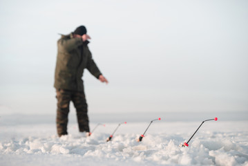 Winter fishing smelt.. Focus on the fishing rod. Fisherman in the background