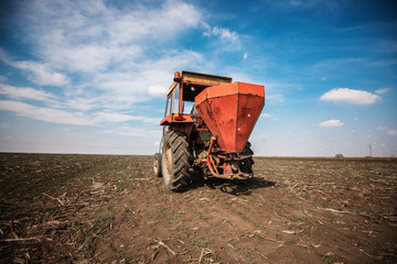 Farmer fertilizing arable land with nitrogen, phosphorus, potassium fertilizer 