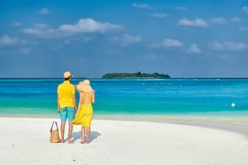 Fototapeta na wymiar Couple in yellow on tropical beach at Maldives