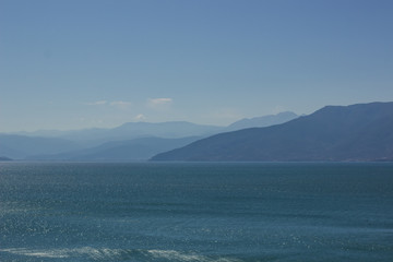 abstract blue landscape of foggy mountain silhouette background and sea foreground 