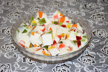 Gelatin Dessert Homemade on cakestand on light background. Glaze dessert for kids and adults. Multicolored gelly cut into square pieces on a big plate.