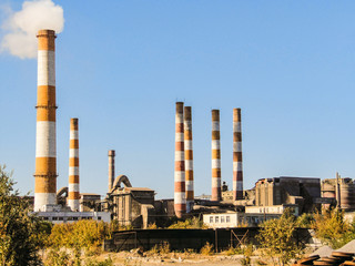 Fototapeta na wymiar Old factory chimneys on industrial site area. Environmental pollution.