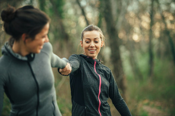 Two young beautiful woman exercise in the forest