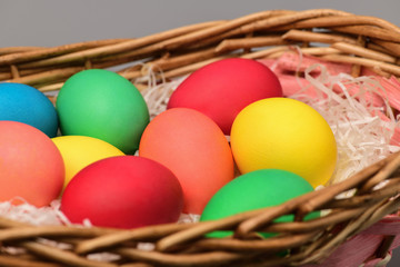 Easter eggs are colorful in a wicker basket on a gray background. happy Easter. Horizontal photography.