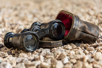 old binoculars on pebbles