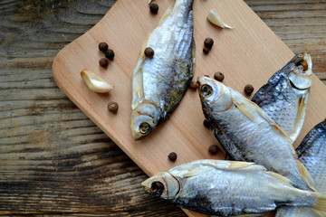 Salty stockfish cod on wooden board with gaarlic and pepper