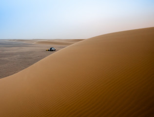 Desert atmosphere in the morning in the desert Sahara in Sudan on a big sand dune with the tent and the jeep in the background, Africa