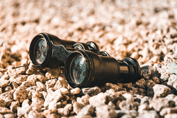 old binoculars on pebbles