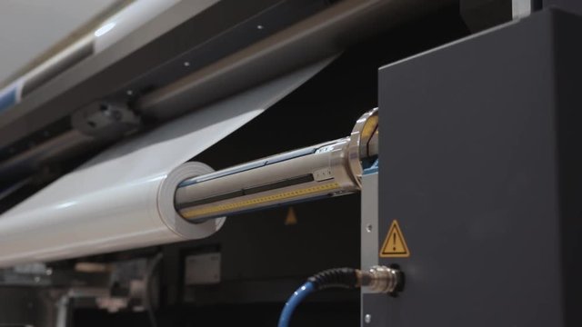 Professional  printing facility, big vinyl rolls, ready for large printer supply. Glossy, matte, ecological paper tubes, details and close up shot of mechanical movement during press and publishing.