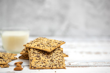 Cup of almond milk and stack of whole grain biscuits on light background. With copy space