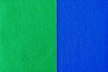Fototapeta premium Two pieces of blue and green felt. Surface of fabric texture.
