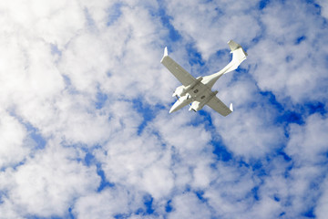 a small private white plane with screws flies on the background  blue sky with clouds