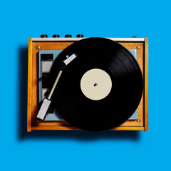 vintage turntable vinyl record player on blue background. retro sound technology to play music