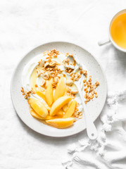 Greek yogurt with poached caramelized pears and granola - delicious breakfast, brunch, dessert on a light background, top view