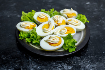 plate with hard-boiled eggs, with the addition of mayonnaise and green leaves of lettuce