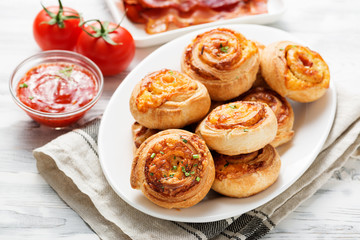 Rolls of puff pastry with bacon and cheese .