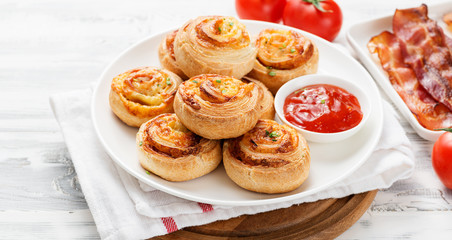 Rolls of puff pastry with bacon and cheese .