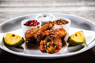 Grilled chicken drumsticks with pear on wooden background