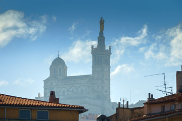 Fototapeta na wymiar Basilique Notre-Dame de la Garde in the foggy background with red tiled roof Marseille houses