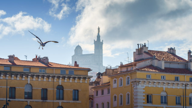 Basilique Notre-Dame de la Garde in the foggy background with red tiled roof Marseille houses - Powered by Adobe