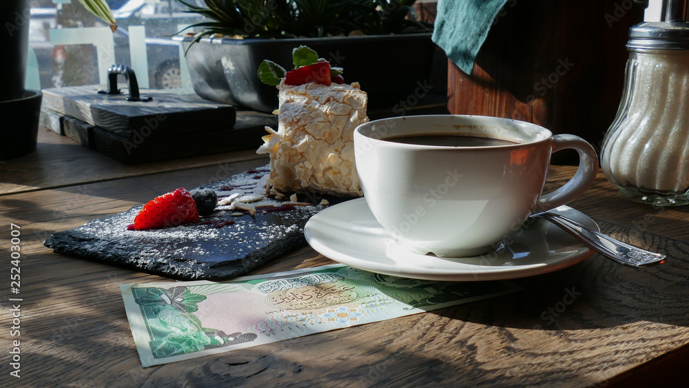 Wall mural Kuwaiti banknotes lying under a cup of coffee 