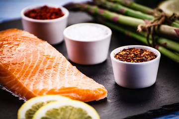 Fresh raw salmon fish served on black stone on wooden table