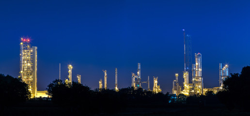 petrochemical and petroleum plant industry with refinery stack and tank farm in in chemical industrial zone at night after sunset