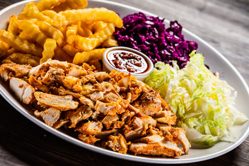 Kebab - grilled meat with french fries and vegetables on wooden background