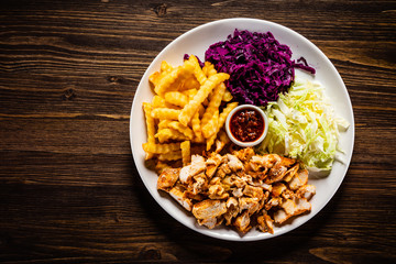 Kebab - grilled meat with french fries and vegetables on wooden background