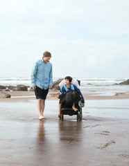 Father on beach with disabled son in wheelchair