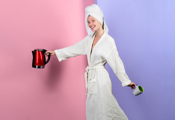 Girl with electric tea kettle and cup. Happy housewife hold red kettle and mug. Beautiful woman in...