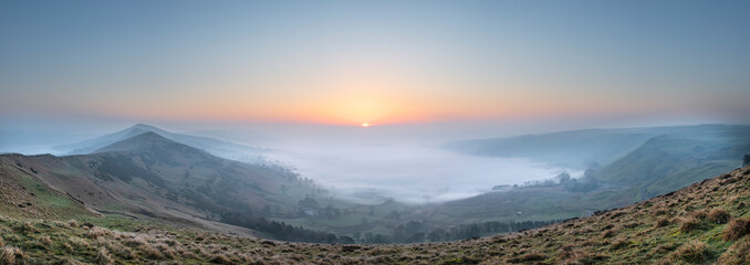 Stunning Winter sunrise landscape image of The Great Ridge in the Peak Distrit in England with a cloud inversion and mist in the Hope Valley with a lovely orange glow