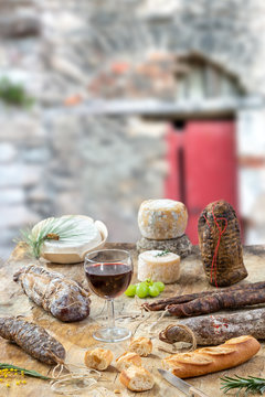 Corsican wild pork delicatessen, and cheese made in Corsica France on old wall background with a glass of corsican wine