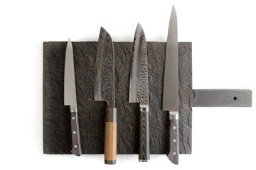 Four different knives on black cutting board, isolated