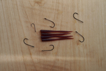 Colorful silicone fishing baits with plummets on wooden table. Various fish and worms and crayfish....