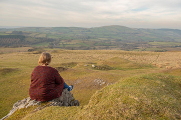 Fototapeta na wymiar Mature woman sitting outdoors overlooking rural view