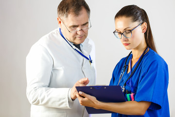 The doctor looks at the results of the nurse's records in the card, while in the hospital