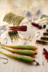 Colorful silicone fishing baits with plummets on wooden table. Various fish and worms and crayfish. Toned image and top view. Stock background, photo