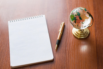 Top view of Blank notebook white paper and globe world map on wooden background with space for your message.
