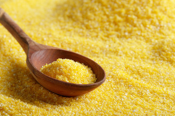 Corn grits yellow background with wooden spoon