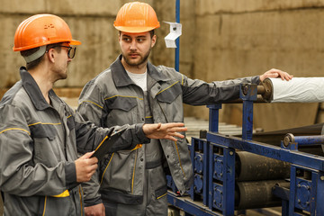 Two industrial workers checking stock with a clipboard