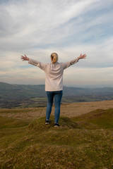 Young woman with outstretched arms overlooking rural view